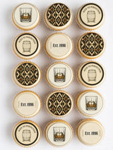 Decorated cupcakes with elegant black and gold edible cupcake toppers featuring whiskey-themed designs on white frosting