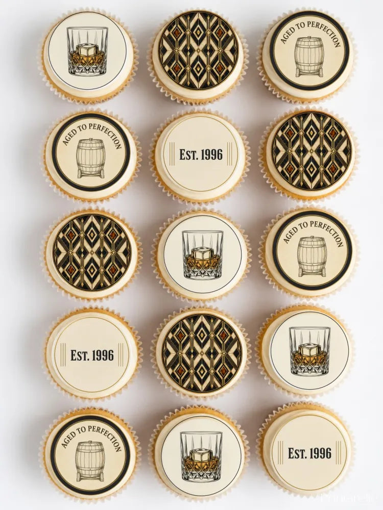 Decorated cupcakes with elegant black and gold edible cupcake toppers featuring whiskey-themed designs on white frosting