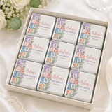 A white gift box of mini neapolitan chocolates with pastel floral wraps and colorful alphabet blocks spelling baby