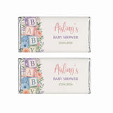 Pastel-colored baby shower chocolate bars wrapped in silver foil with floral and alphabet blocks shower design