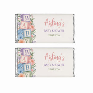 Pastel-colored baby shower chocolate bars wrapped in silver foil with floral and alphabet blocks shower design