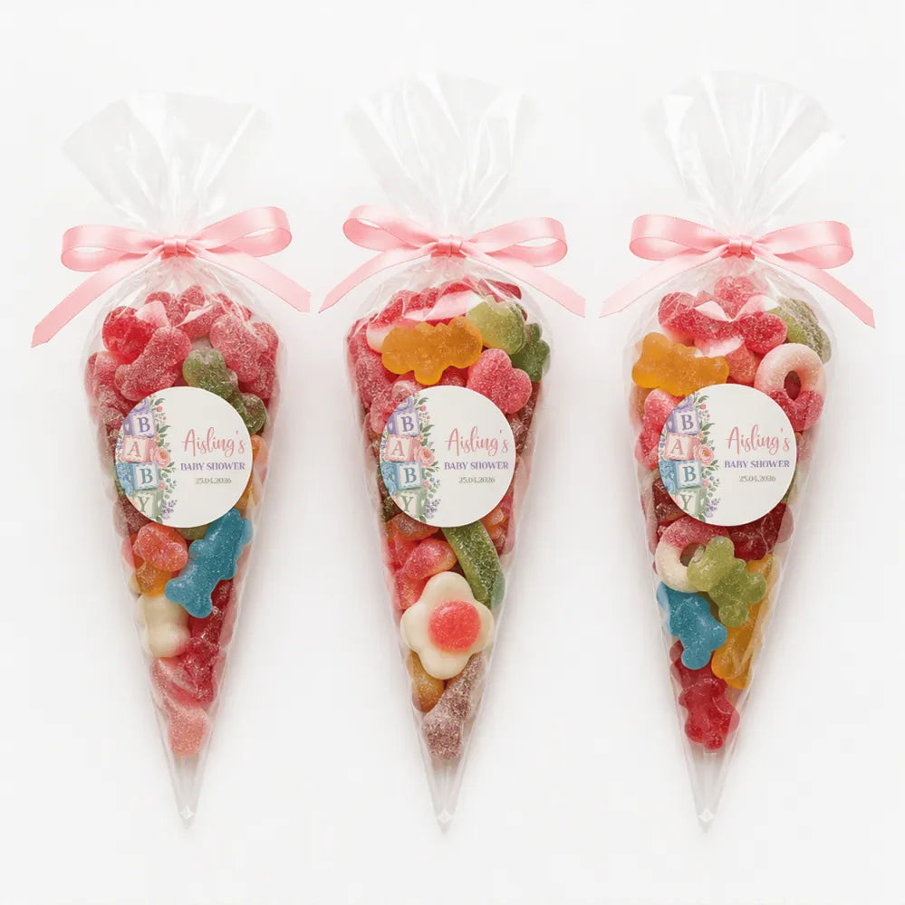 Three clear plastic sweet cones tied with pink ribbons filled with colorful gummy candies for aisling’s alphabet blocks shower