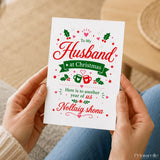 A festive white husband christmas card with red green holiday illustrations and message to my husband at christmas in white envelope