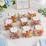 Clear box filled with colorful sugar-coated gummies sealed with a blessed cross label in a clear acrylic box