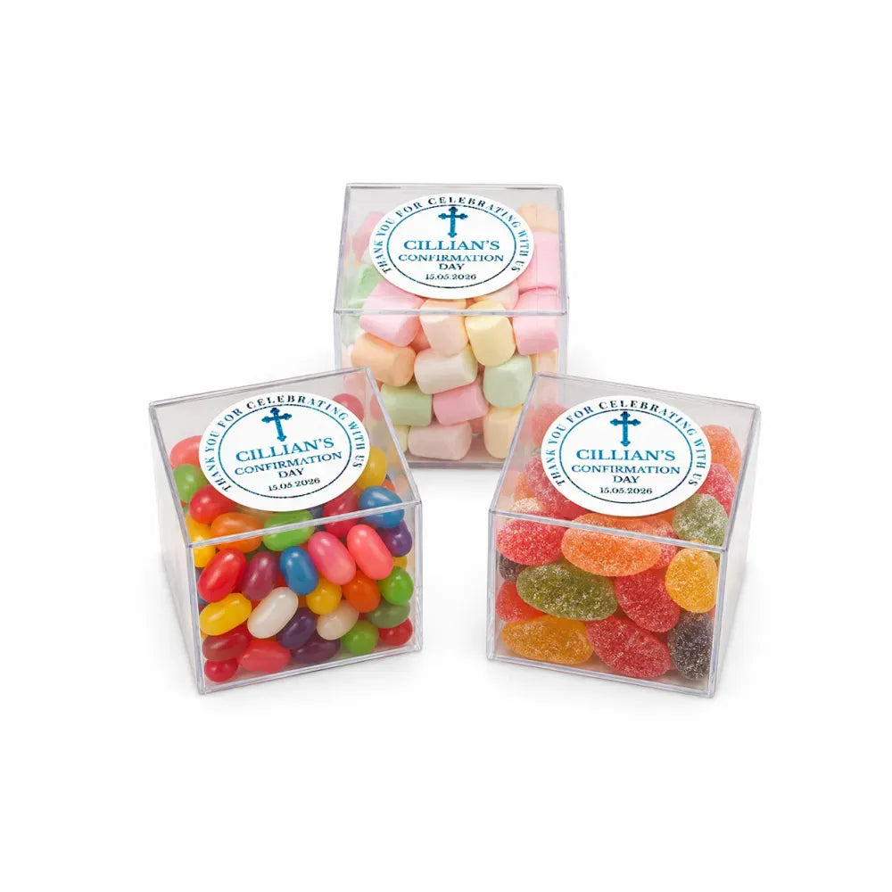 Three colorful candy-filled clear acrylic boxes sealed with white blessed cross stickers perfect for confirmation gifts