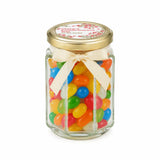 A clear glass personalised hex jar favour with 48mm pale gold lid cream ribbon bow filled with colorful jelly beans