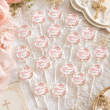 Pink floral patterned lollipop favours with pink blossoms in clear wrappers labeled claras confirmation day 10.04.2026