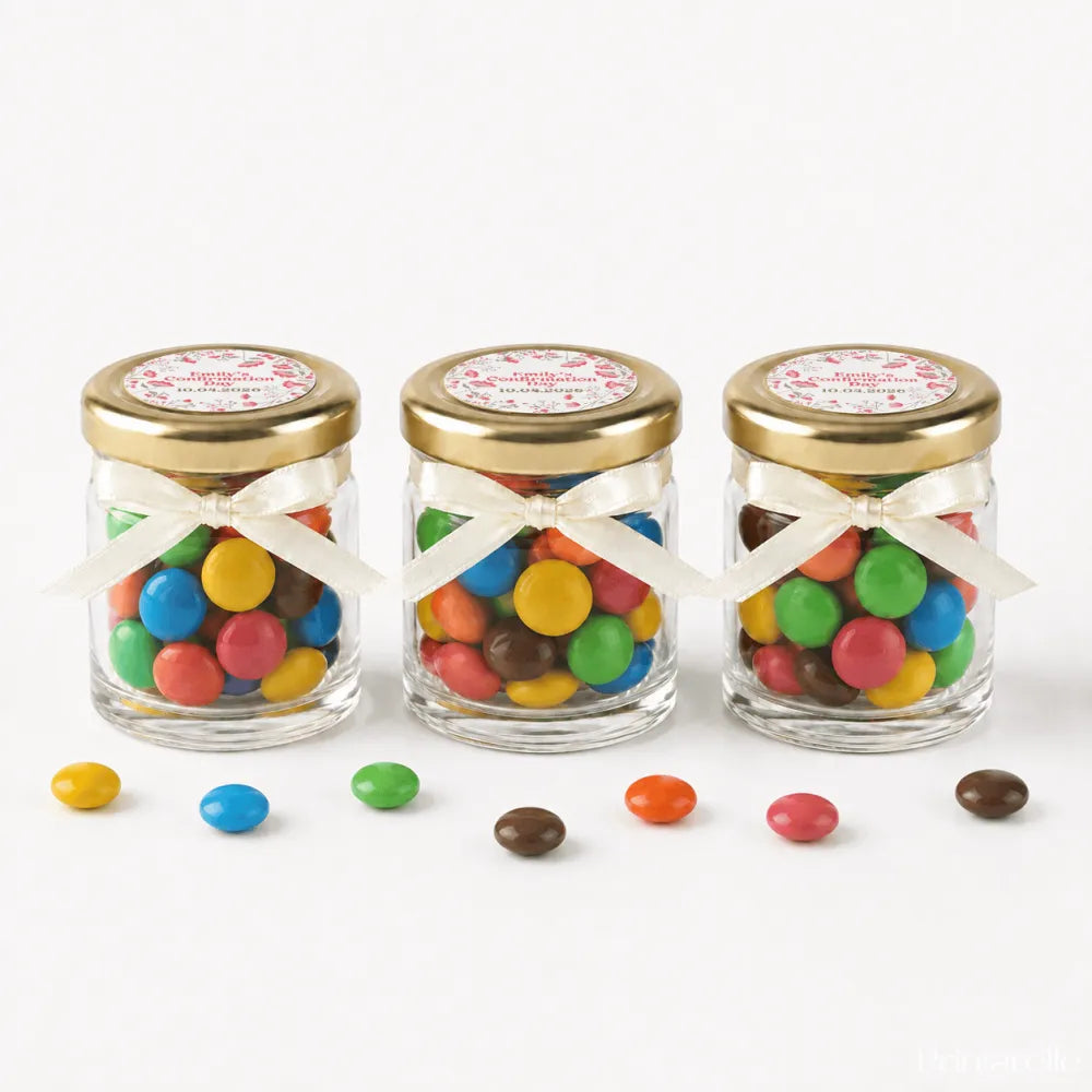Three clear glass personalised mini jar favours with 43mm pale gold lids and pale gold twist ribbons filled with candy