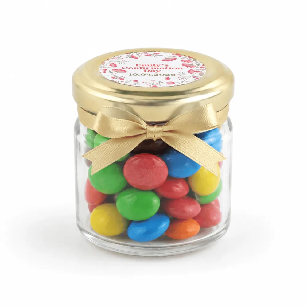 A clear glass jar with a 43mm pale gold twist lid and personalised sticker printed filled with colorful candy for confirmation favors