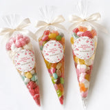 Three clear cellophane sweet cones tied with cream ribbons filled with colorful gummies for personalised confirmation day favors