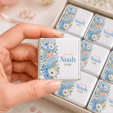 A personalized white chocolate mini neapolitan wrapped in silver foil with blue floral design and a baby named noah