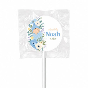 A personalized blue swaddle baby lollipop favour with white floral swirl and welcome baby noah 25.11.2016 label