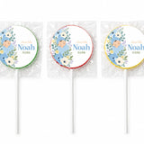 Three blue swaddle lollipop favours with personalized baby noah illustration and arrival date on white labels