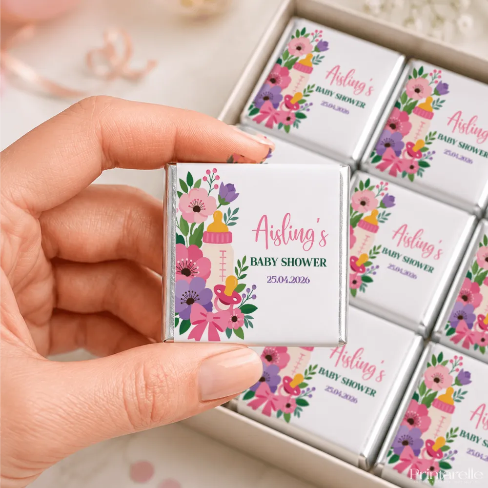 A white chocolate wrapper with colorful pink and purple flowers and a baby bottle for mini neapolitan chocolates
