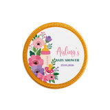 A round gold-edged milk chocolate coin with baby shower design featuring pink purple flowers and a pacifier
