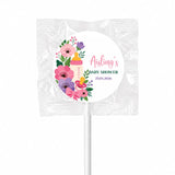 A pink and purple floral baby shower lollipop favour with a yellow baby bottle design wrapped in clear foil