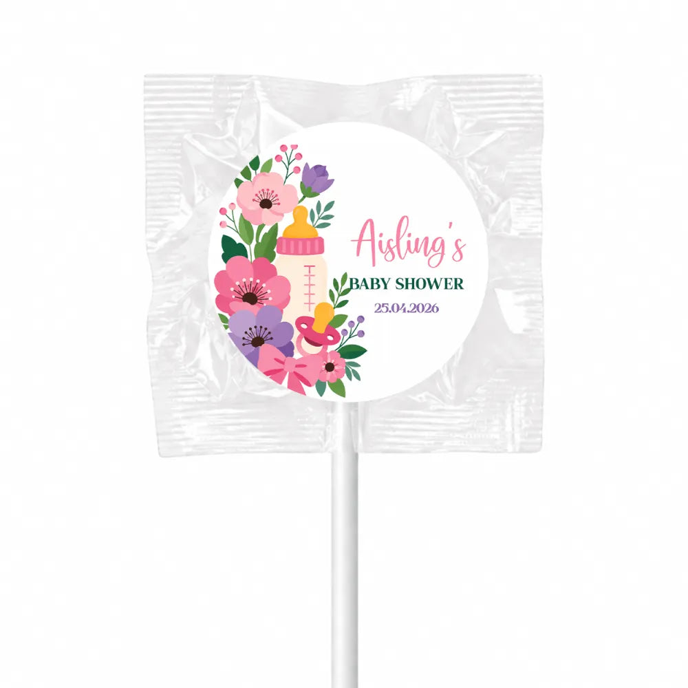 A pink and purple floral baby shower lollipop favour with a yellow baby bottle design wrapped in clear foil