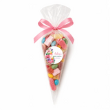 A clear plastic sweet cone filled with colorful gummies and marshmallows topped with a pink satin ribbon for a baby shower