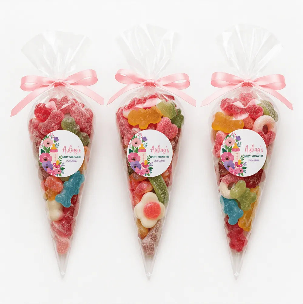 Three clear plastic sweet cones tied with pink ribbons filled with colorful candy for aisling’s baby shower gift