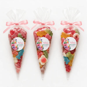 Three clear plastic sweet cones tied with pink ribbons filled with colorful candy for aisling’s baby shower gift