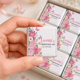 A pink and white floral mini neapolitan chocolate square with a baby carriage design wrapped in silver foil