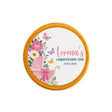 A round gold-edged chocolate coin with a pink butterfly pram and floral illustrations for christening gifts