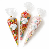 Three clear plastic sweet cones tied with gold twist ties and floral labels filled with colorful christening sweet cones