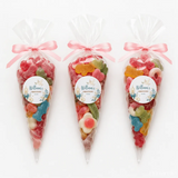 Three clear plastic sweet cones with shell design filled with colorful gummies tied with pink ribbon for christening sweet cones