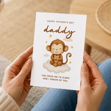 Person holding a Father's Day card with a monkey illustration and text.