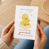 Person holding a Father's Day card with a yellow duck illustration on a blurred background