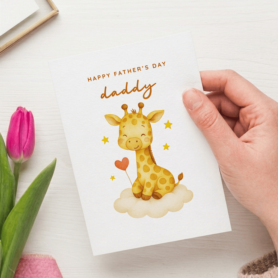 Hand holding a Father's Day card with a giraffe illustration and pink tulips on a white surface.