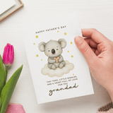 Hand holding a Father's Day card with a koala illustration and text, next to a pink tulip.