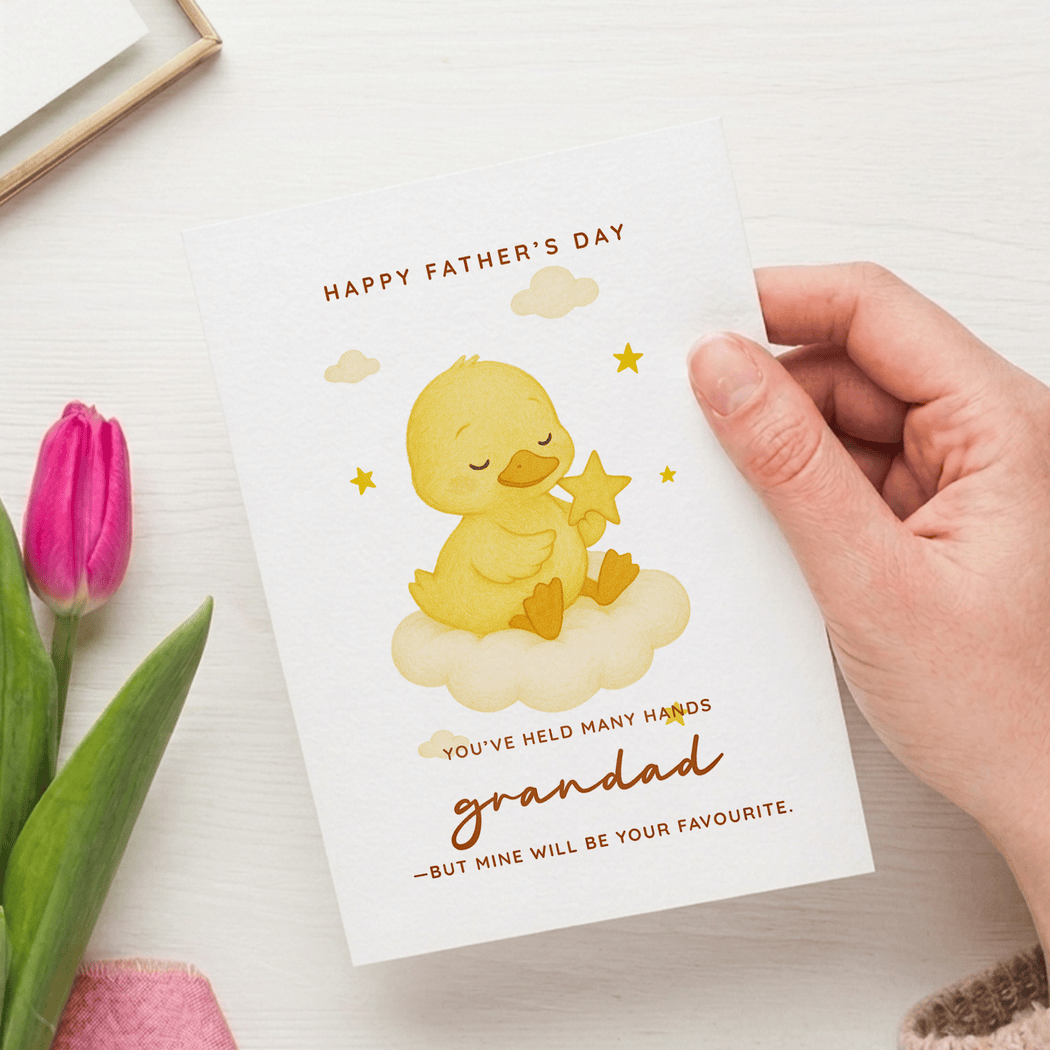 Hand holding a Father's Day card with a yellow duck illustration and text.