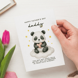 Hand holding a Father's Day card with a panda illustration and pink tulip on a white surface.