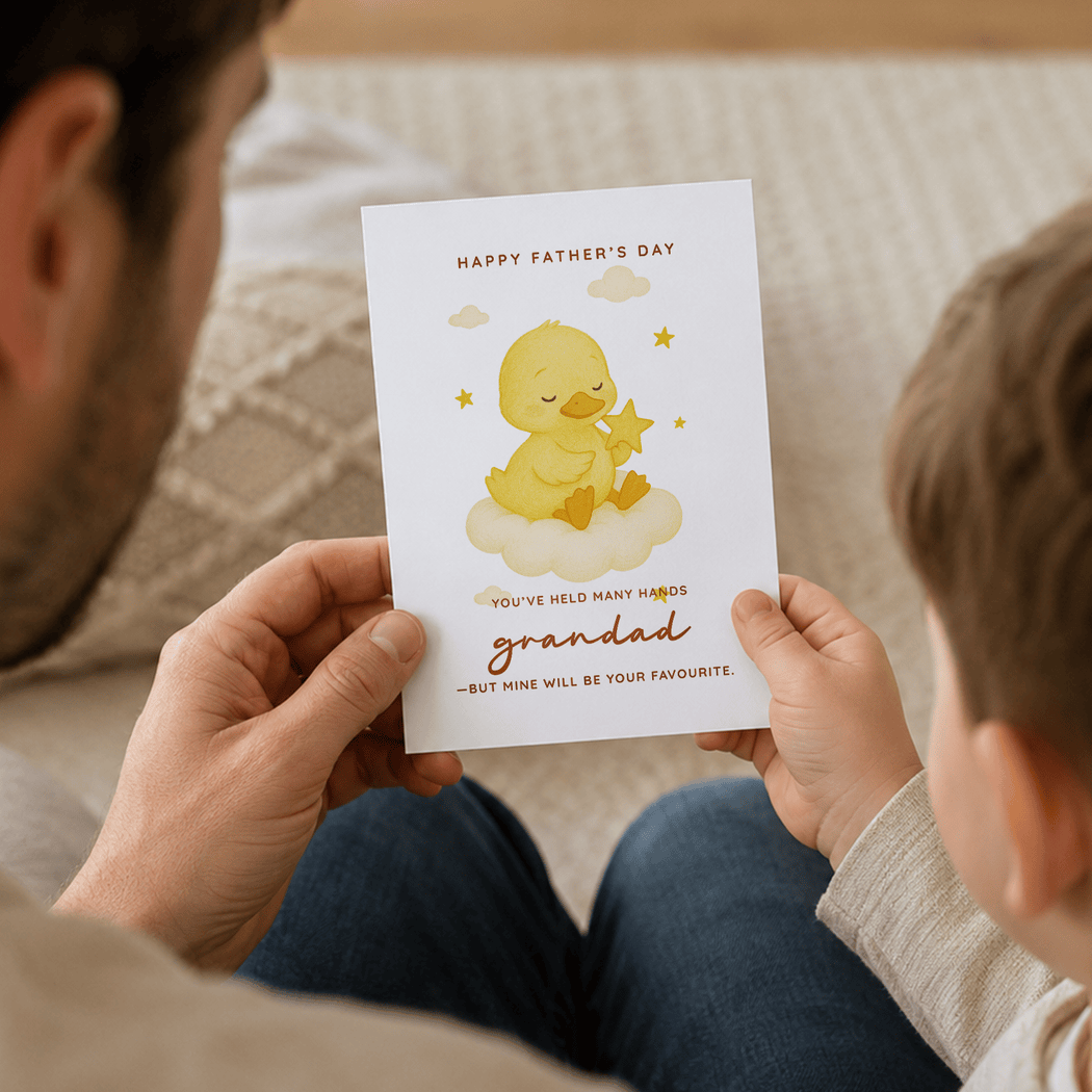 Person and child holding a Father's Day card with a yellow duck illustration.