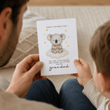 Person holding a Father's Day card with a koala illustration and text.