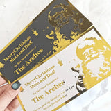 Two Christmas gift cards with gold text and images of a couple, held by a hand.