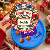 A festive red and green personalised tub sticker with christmas treats text and sophie name on a cadbury roses container