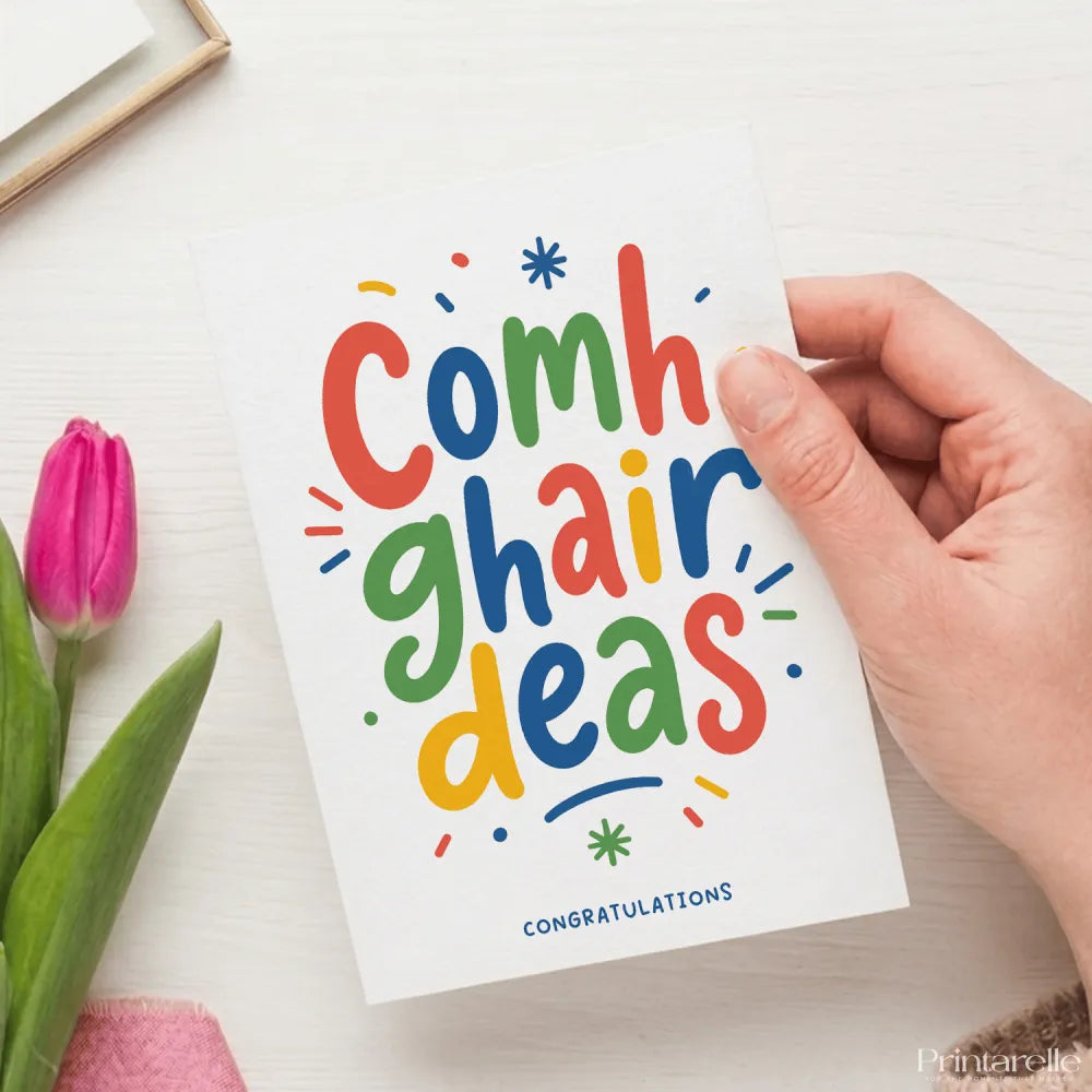 Colorful hand-held irish congratulations card with vibrant rainbow lettering and decorative elements saying comhghairdeas
