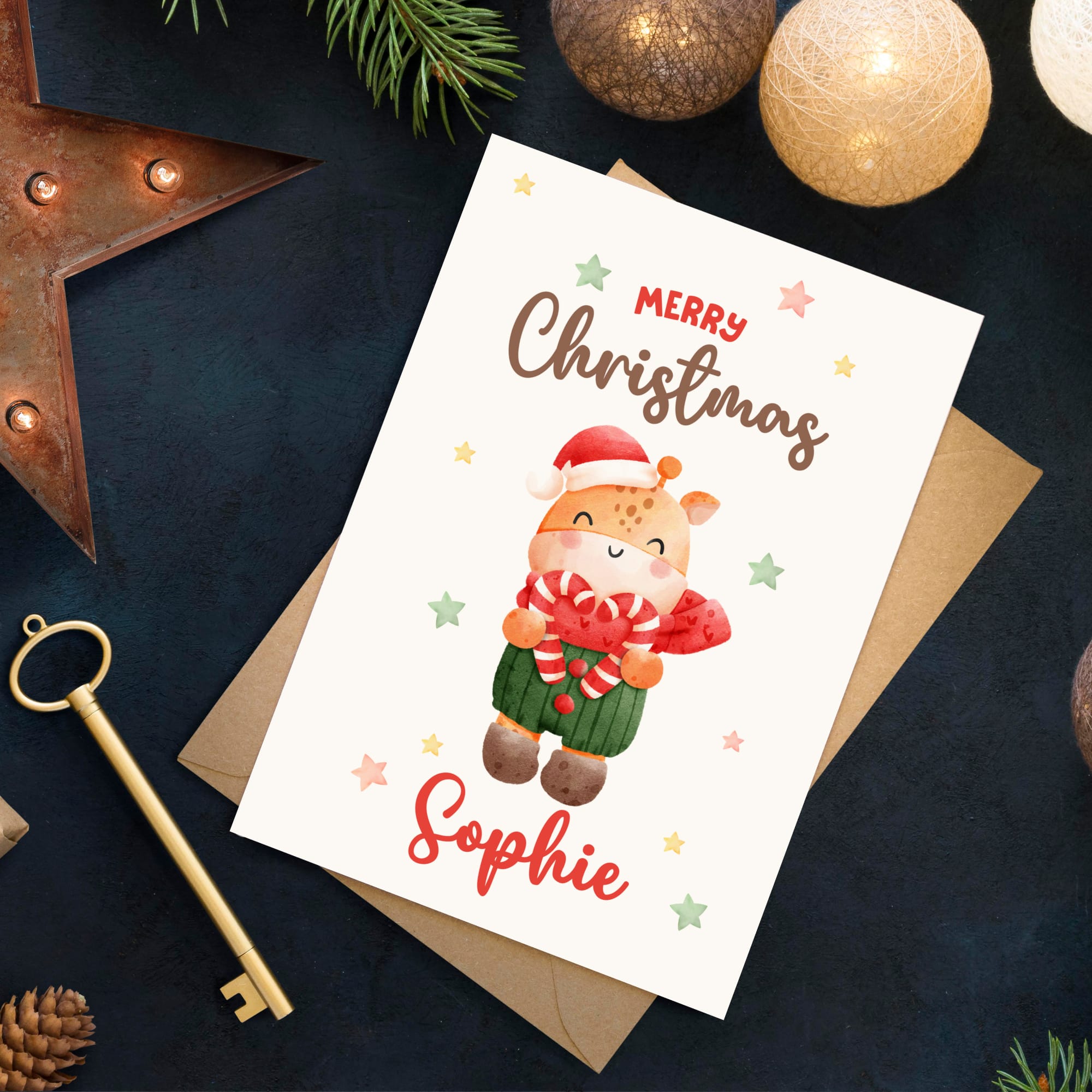 Christmas card with a reindeer illustration and 'Merry Christmas Sophie' text, surrounded by festive decorations on a dark surface.
