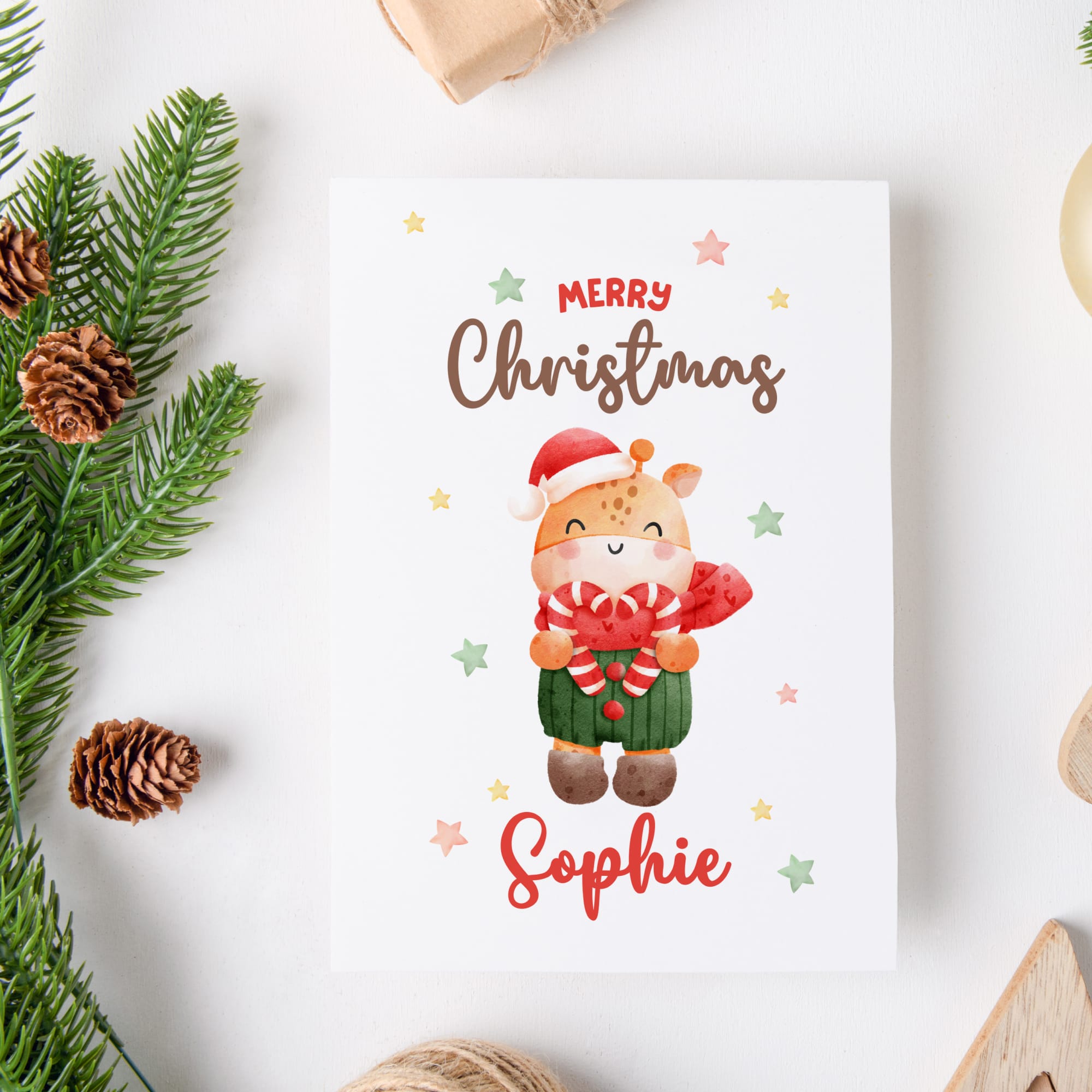 Christmas card with a cartoon reindeer wearing a Santa hat and scarf, surrounded by Christmas decorations on a white background.