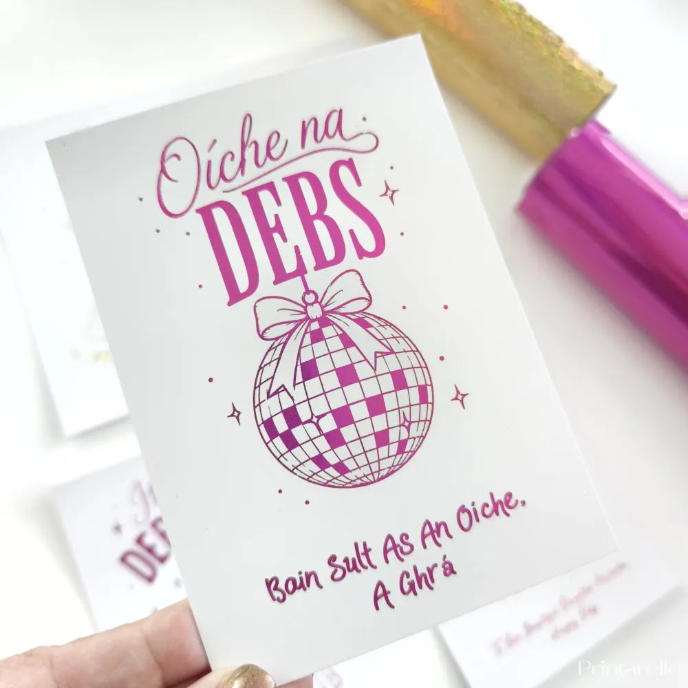 A white debs card with pink text and a checkered disco ball featuring holographic blue foil for debs night celebration