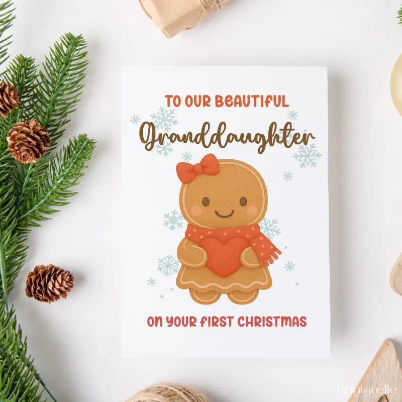 Greeting card with a gingerbread girl design and text for a granddaughter's first Christmas, surrounded by Christmas decorations.