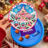 A festive blue cadbury roses tub with a merry christmas fairytale castle tub sticker and colorful lid design