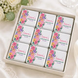 Nine mini neapolitan chocolates with colorful floral designs and lauras christening day text in white gift box
