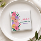 A personalized white chocolate mini neapolitan with pink purple yellow floral design and a wrapped baby illustration