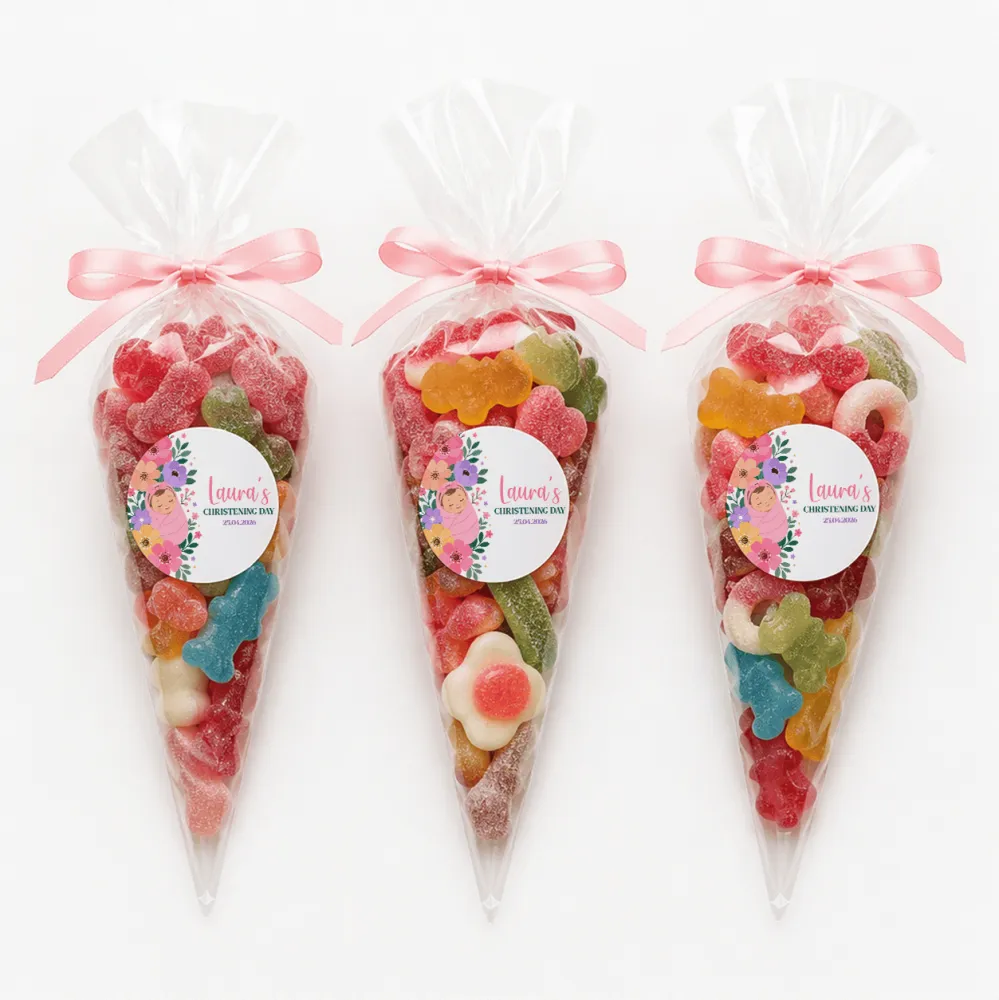Three clear plastic sweet cones with pink ribbons and floral swaddle labels filled with colorful gummy candies