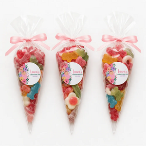 Three clear plastic sweet cones with pink ribbons and floral swaddle labels filled with colorful gummy candies