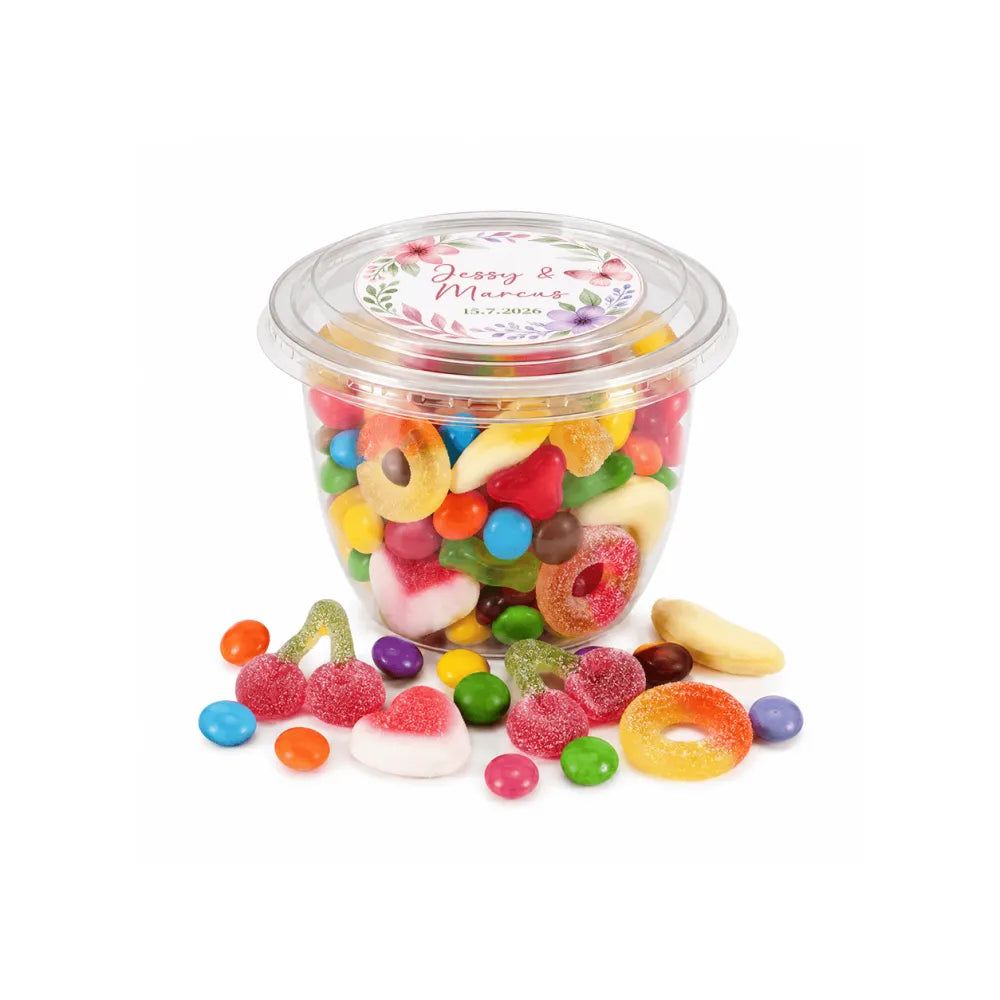 A clear plastic container of colorful gummy candies with a floral wreath foiled sticker lid dated 15.7.2026