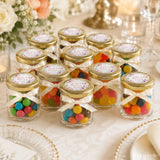 Clear glass jars with gold lids and cream ribbon bow filled with colorful gummy candies for floral wreath wedding favours